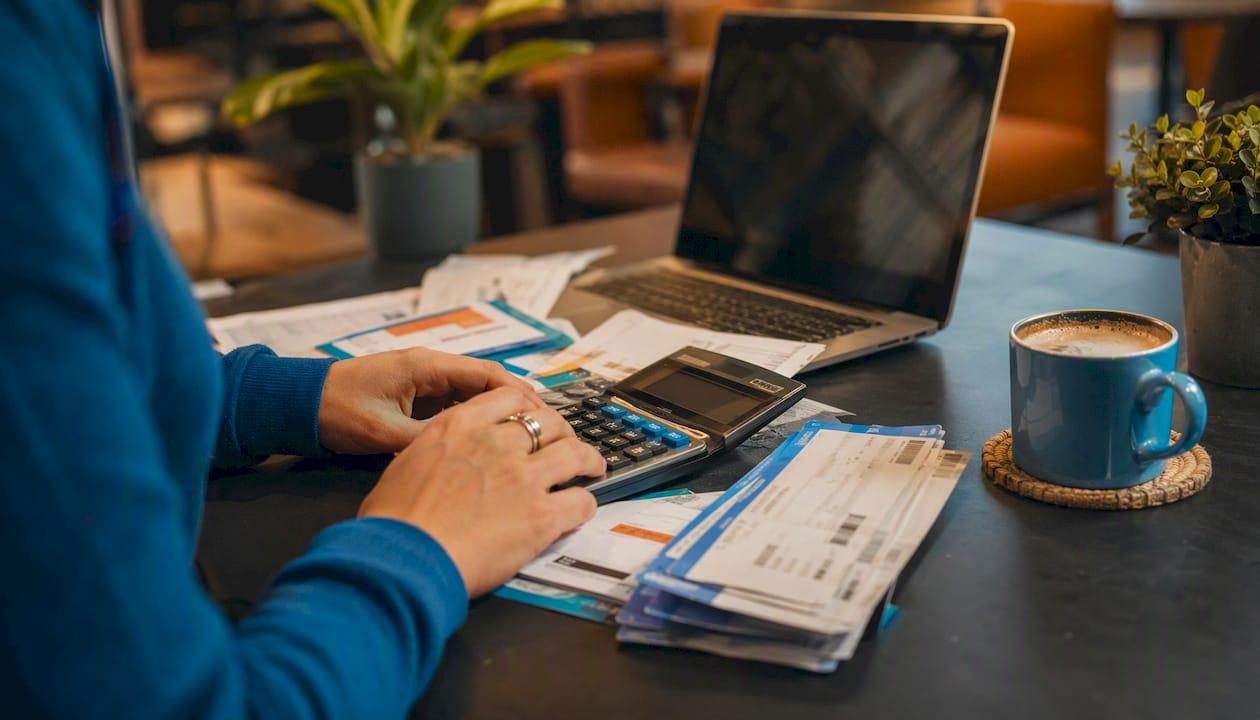 Hands calculating total flight cost at desk